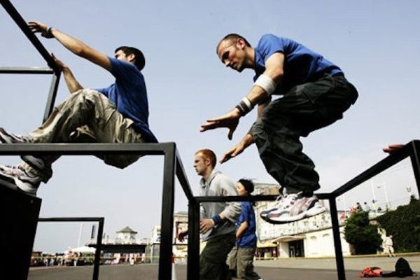An image of a group of male performers jumping over a climbing frame.
