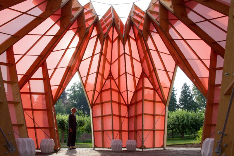 An image of a man stood inside a large pink abstract sculpture