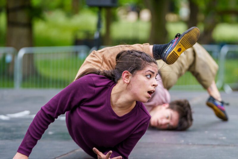 An image of two female dancers writhing around on the floor. They are both wearing pink tops.