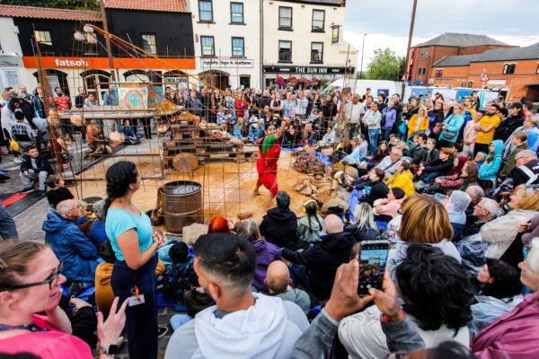 An image of a crowd of people surrounding a makeshift stage.