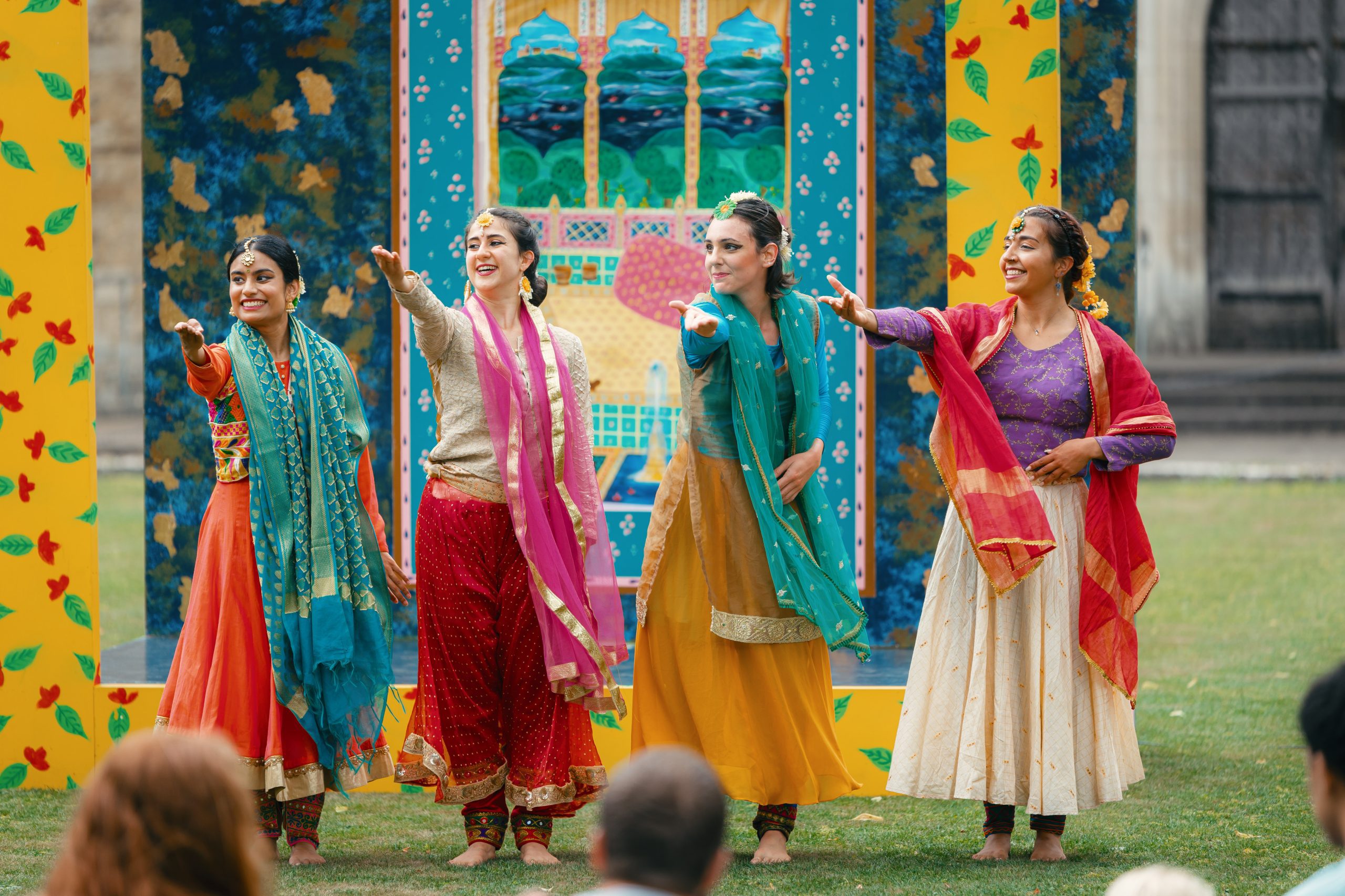 An image of four dancers wearing bright and colourful traditional Indian dress