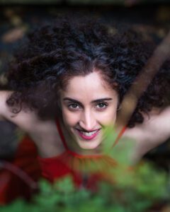 An image of a woman with long dark curly hair looking up at the camera.