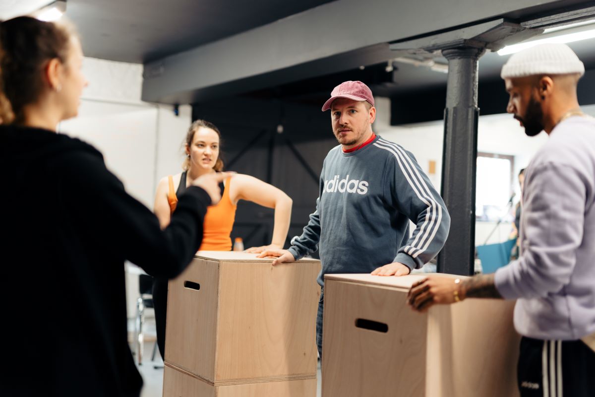 An image of two males and two females carrying cardboard boxes.