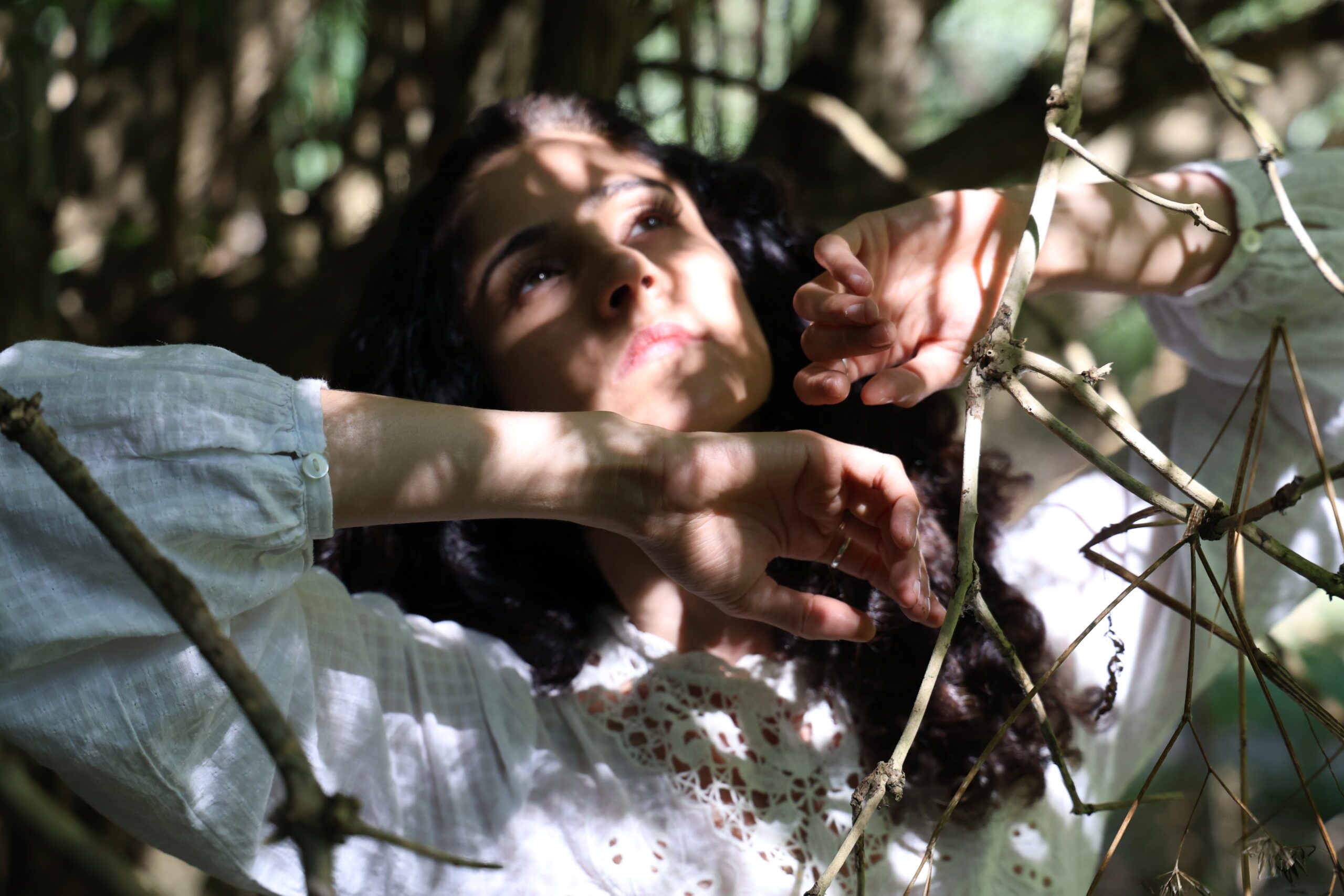An image of a female dancer with long dark hair wearing a white top.