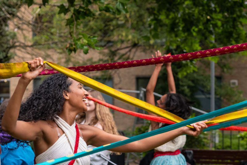 An image of two South Asian female dancers dancing around a maypole.