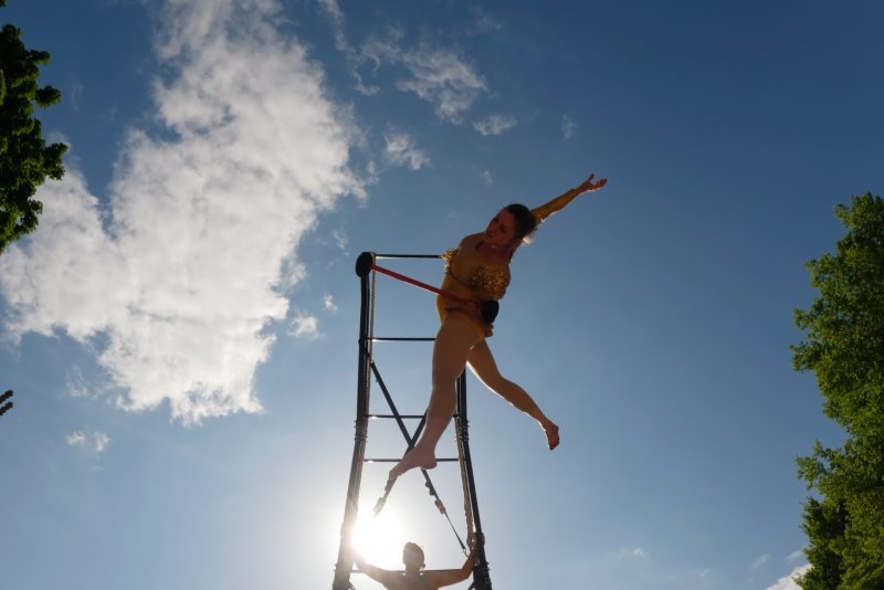 An image of a silhouette of a trapeze artist balancing on a plinth with a blue sky sunny background
