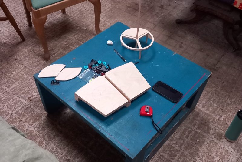 An image of a blue square table with various tools, blocks and a tape measure.