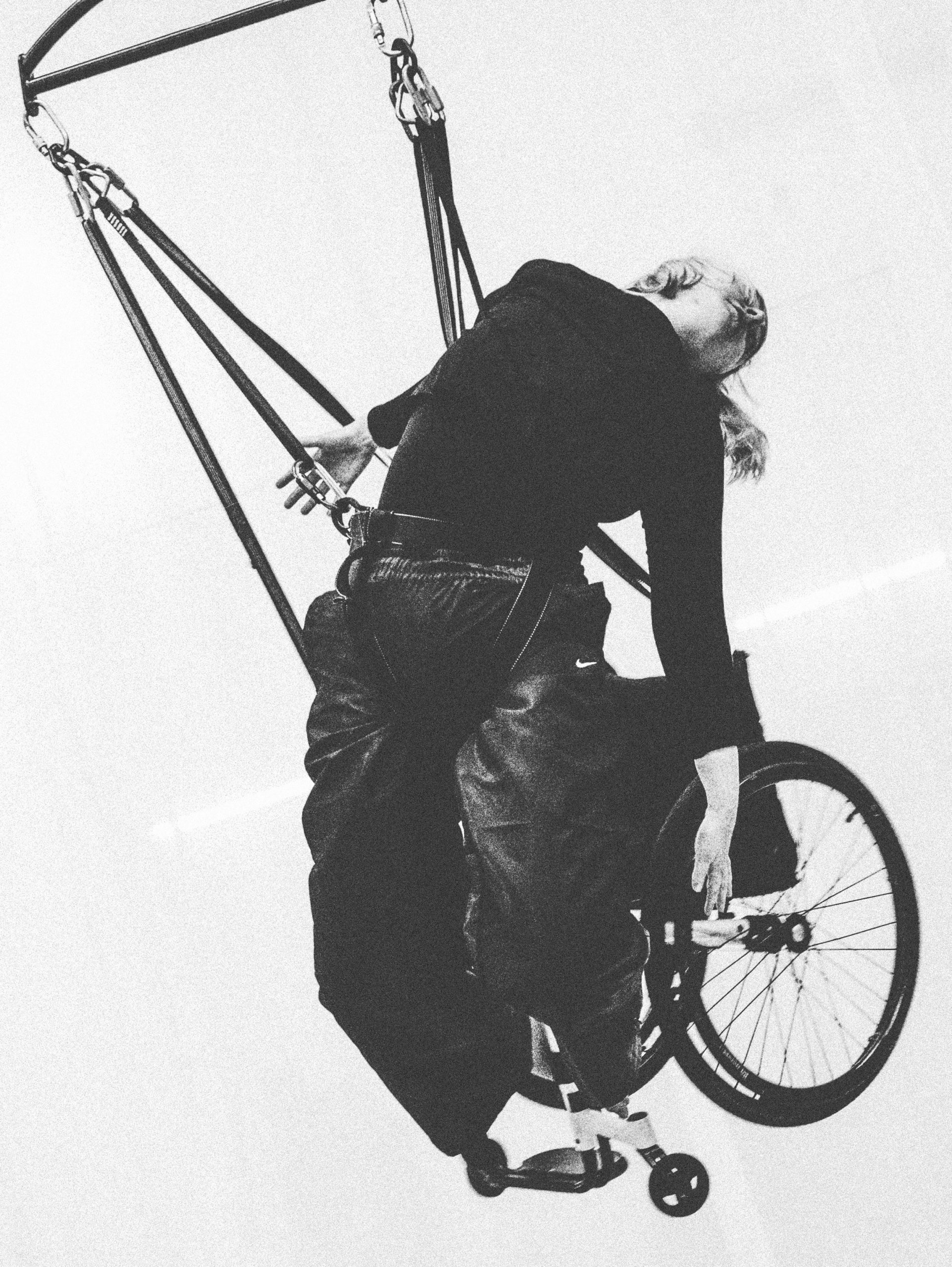 A black and white image of a female trapeze artists swinging from a makeshift swing.