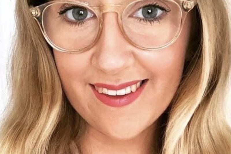 A portrait image of a white woman with long blonde hair wearing glasses.
